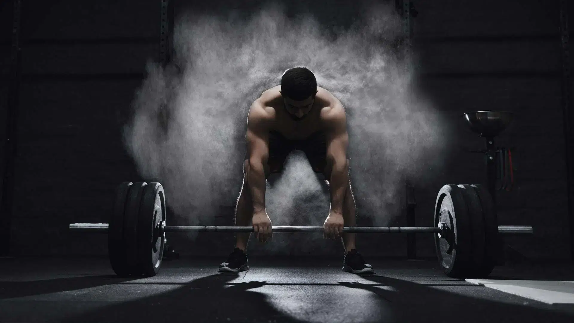 man in donkerlicht doet een deadlift